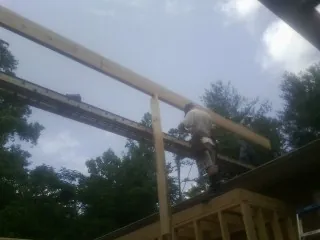 Carpenter setting a ridge beam over a new addition frame — Ice Dam Removal by Roofing Brothers in Martin City