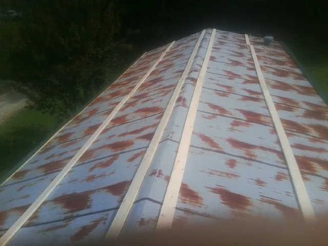 Rusted metal roof panels with new wood purlins before replacement — Storm Damage Roof Repair in Martin City by Roofing Brothers