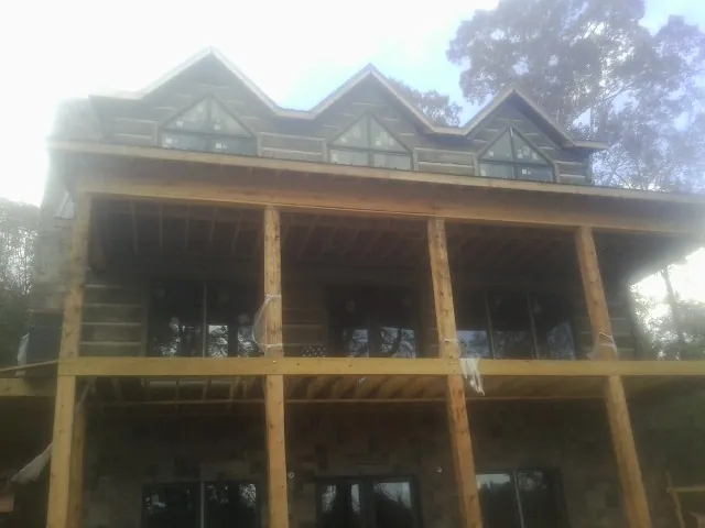 Dormers and porch framing on a large log home under construction — Roof Coating work by our crew in Martin City