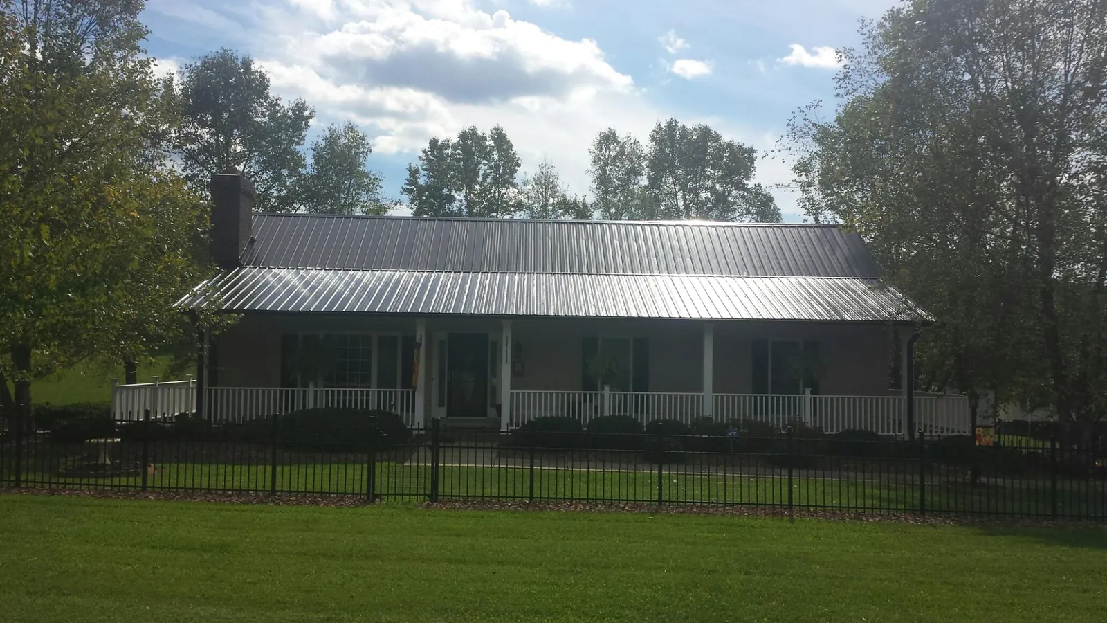 Gray metal roof on a brick ranch with a full width front porch — Gutter Guard Installation work by our crew in Martin City