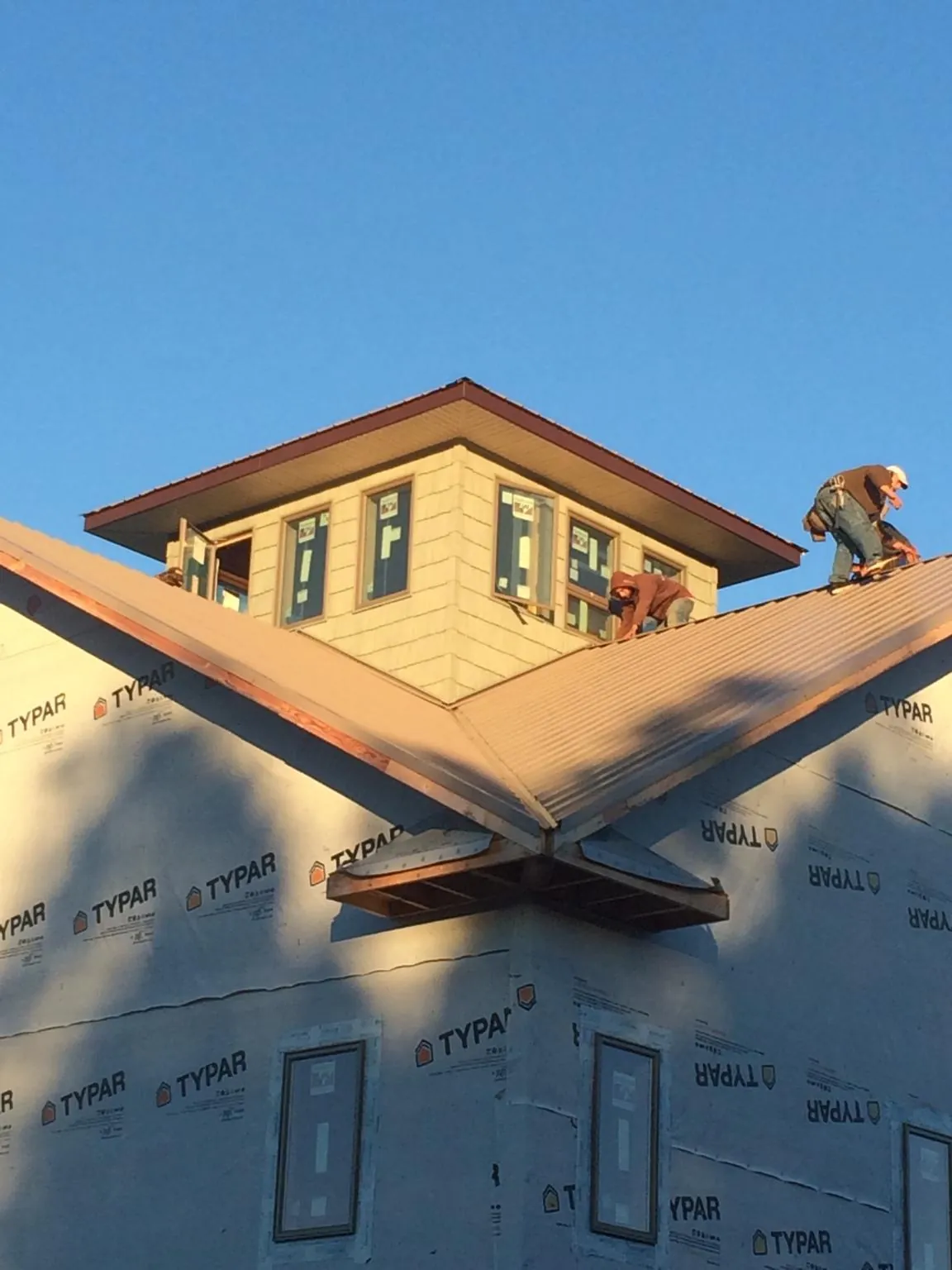 Roofers working around a rooftop cupola on a new metal roof at sunset — Roof Waterproofing in Martin City by Roofing Brothers